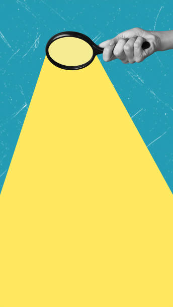istock Modern art collage featuring a hand with a magnifying glass and yellow ray on blue background. 2192263667