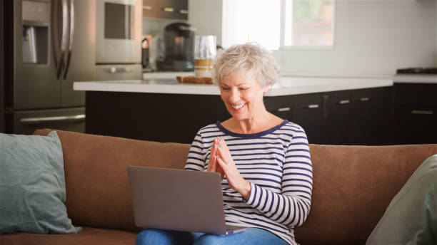 istock Senior Woman On Sofa At Home Using Laptop Browsing Online Streaming Show Or Checking Messages 2192265887
