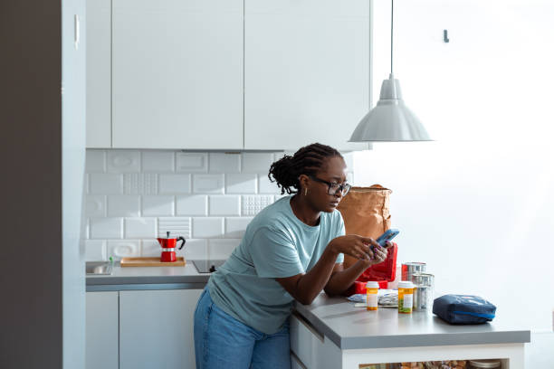 istock Woman using smartphone in the kitchen with medications and canned goods 2192270082