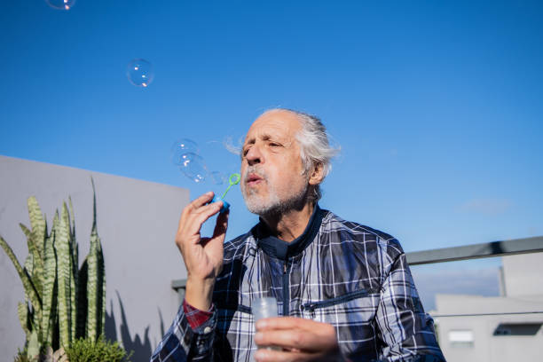 istock Senior man playing with bubble wand on rooftop 2192271841