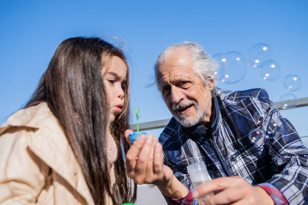 istock Senior man and granddaughter playing with bubble wand at backyard 2192271842