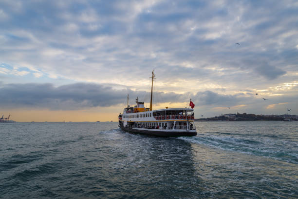 Istanbul, Turkey - November 11, 2024: A ferry passes near Maidens Tower as it crosses the Bosphorus strait