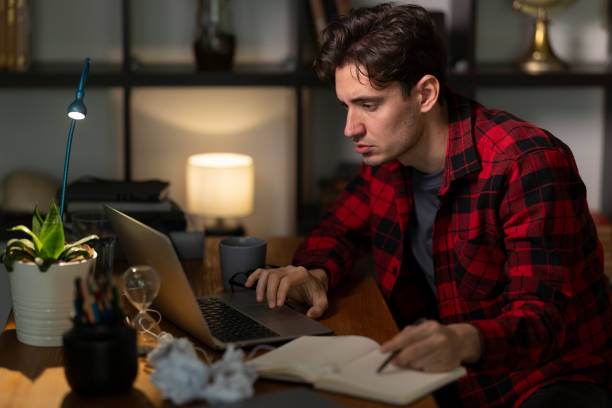 istock Focused young man working late on laptop at home office 2192272410
