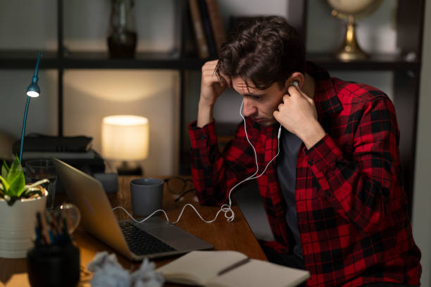 istock Focused young man listening to podcast while working on laptop at night 2192272421