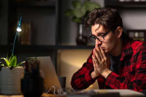 istock Pensive young man working late on laptop at home office 2192272430