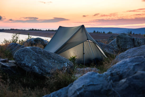 Camping tent in mountains by lake at sunrise