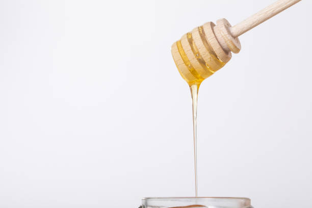 Golden Honey is Dripping Down from a Wooden Dipper, creating a beautiful, sweet sight