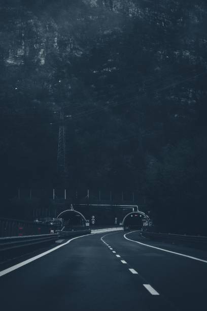 Mountain highway leading into a lit tunnel