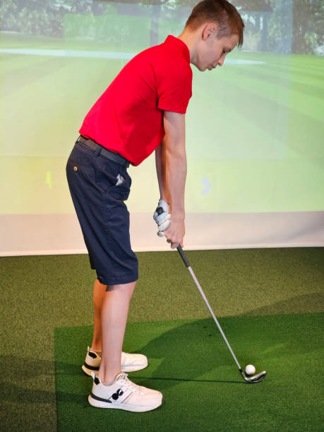 istock Teen boy playing golf on golf simulator on course. Child guy playing golf vertical 2192280957