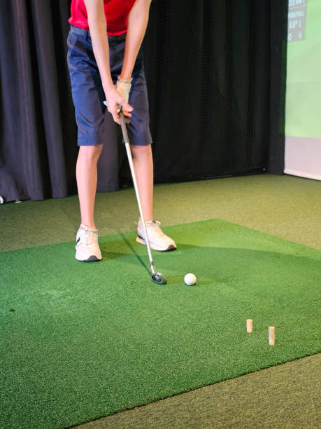 istock Boy plays in a golf simulator indoors. Golfer playing golf vertical 2192280959