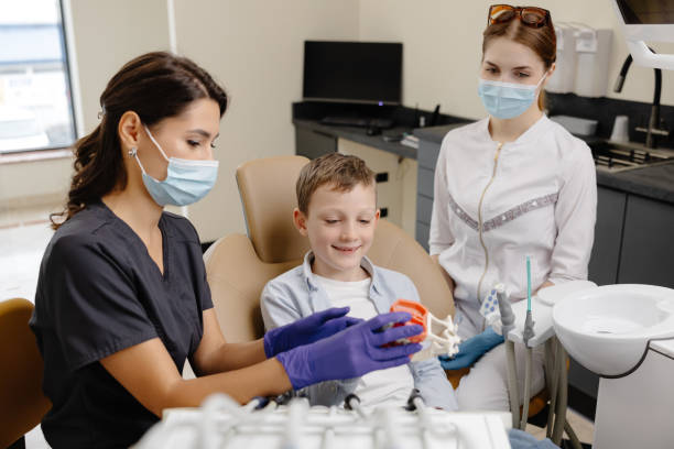 istock Little patient visiting dentist in clinic. Boy playing with teeth model at professional consultation in dentistry office. Kid learning oral hygiene and dental care with doctor 2192283477