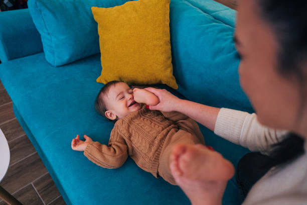 istock A heartwarming scene unfolds on a vibrant turquoise couch as a mother plays with her baby's tiny feet 2192283552