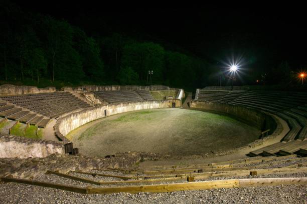 Aerial view of Pula Arena, also known as the Pula Amphitheatre at night. The Arena is an iconic symbol of the city and the best-preserved Roman amphitheatre in the world. Immediately surrounding the arena is Pula's historic old town, characterised by narrow, winding streets and red-tiled roofs. Illuminated buildings and street lights. Istria in Croatia - Eastern Europe.
