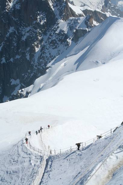 istock Hikers on a snowy mountain path with rugged peaks. 2192285669