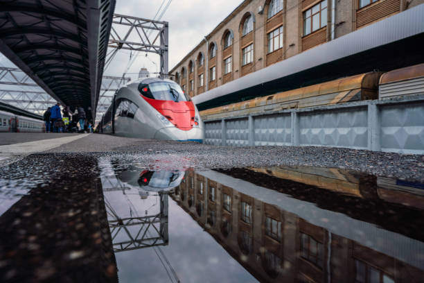 Moscow, Russia - September, 16. 2022: a sleek high-speed train located at a urban railway station, showcasing its modern design. A puddle on the platform beautifully captures the reflection of the scene, enhancing the visual impact.