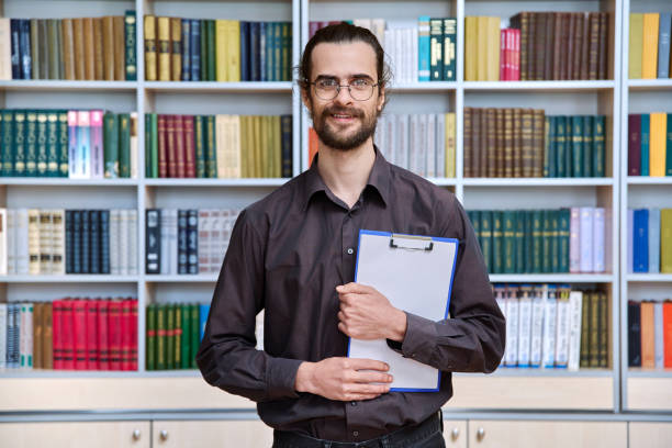 istock Portrait young male with clipboard in library 2192292110