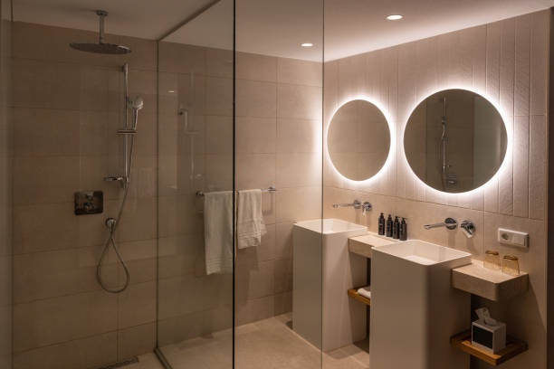 istock Modern bright bathroom with shower and two sinks and illuminated round mirrors 2192292732