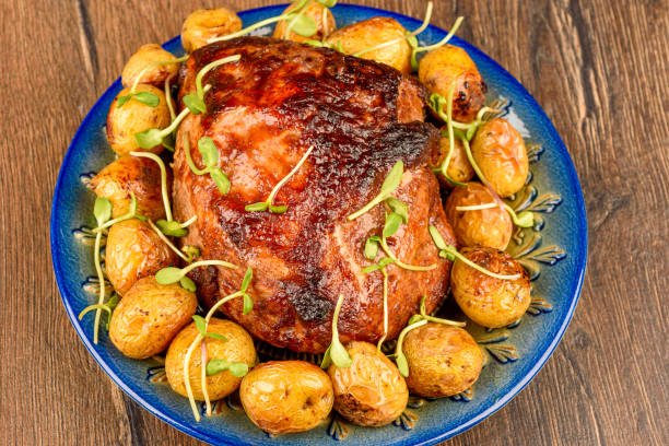 Juicy roasted meat garnished with golden potatoes and fresh sprouts on a rustic blue plate, placed on a wooden background. Concept of hearty meals