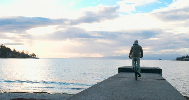 istock Mature man rides bicycle along pier at sunrise 2192296166
