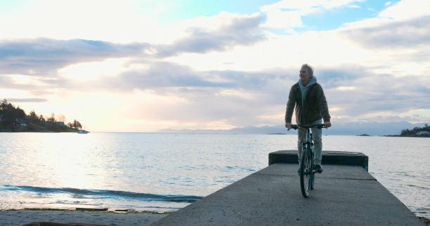 istock Mature man rides bicycle along pier at sunrise 2192296187