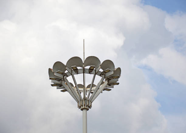 Row of white street lights illuminating in the evening. The lights are white and are hanging from poles