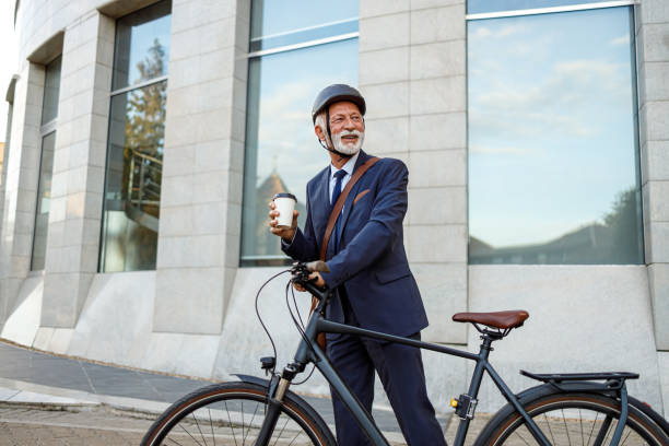 istock Determined senior manager holding coffee cup and looking away while walking with bicycle on street 2192309356