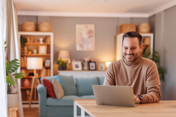 istock Portrait of businessman smiling and analyzing data over laptop while working at desk in home office 2192309469