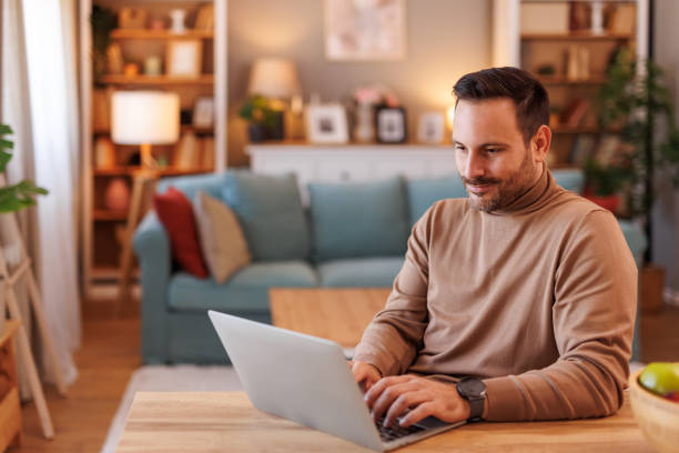 istock Focused handsome freelancer doing online research over laptop while working at desk in living room 2192309476