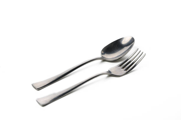 Two silver utensils are arranged peacefully on a white surface, reflecting soft light in a minimalistic style.
