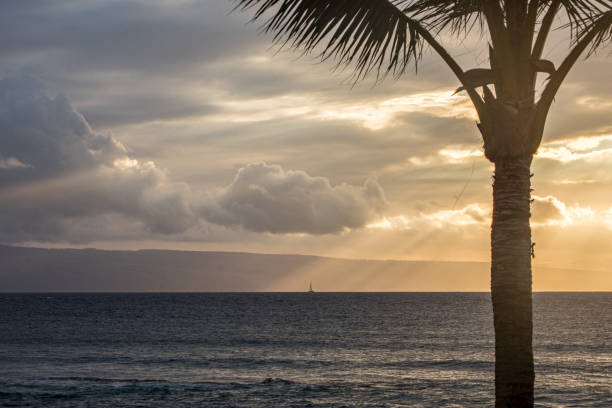 A moody Hawaiian Island cloudscape with sunbeams from a low angle sun.