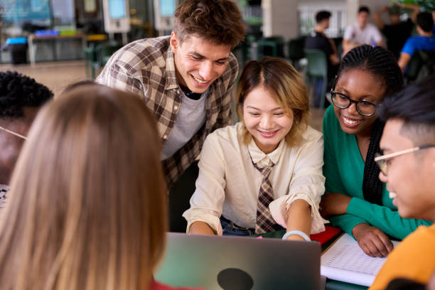 istock Multiracial young group of language students looking smiling at notebook sitting in academy 2192313473