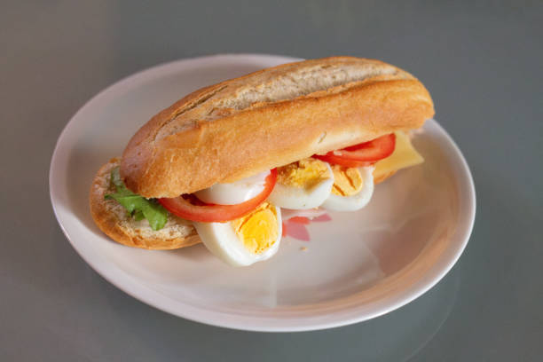 A healthy sandwich is a sandwich, often a piece of baguette, a white bun or a pistolet, topped with cheese, ham, for example, but can also be vegetarian. Tasty Dutch healthy sandwich for lunch with cheese, tomato, egg, vegetarian ham and lettuce. Served on a porcelain plate with knife, fork and napkin
