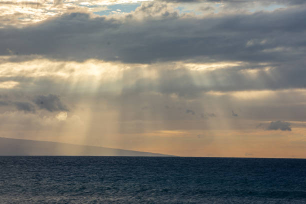 Red sun is setting over the island in Hawai sea waves over clouds sky background