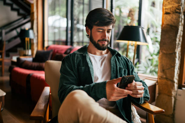 istock Young man using cell phone in the living room 2192318396