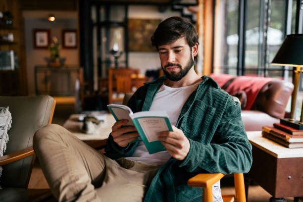 istock Beautiful man reading a book while sitting on a couch in the living room 2192318436