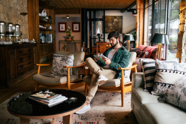 istock Beautiful man reading a book while sitting on a couch in the living room 2192318443