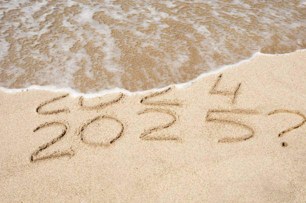 istock Inscription 2024 and 2025 numbers written on sand with question mark. Concept image 2192323771