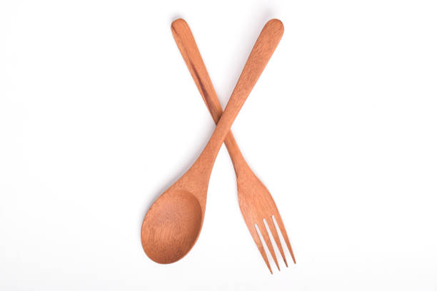 Wooden spoon and fork, crossed as road sign, isolated on white background. Houseware. A set of kitchen utensils