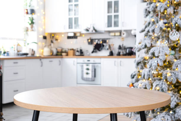 istock Round empty table to demonstrate the product with space for text in white kitchen, modern interior with a Christmas tree and fairy lights. New Year, Christmas mood, cozy home. 2192341607