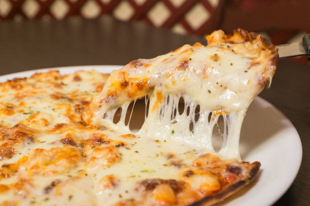 A slice of pizza with cheese on it. The slice is being pulled apart. The pizza is on a white plate