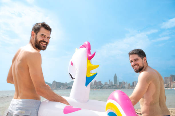 istock Backside Friends with float on beach smiling happy with sea in background 2192348242
