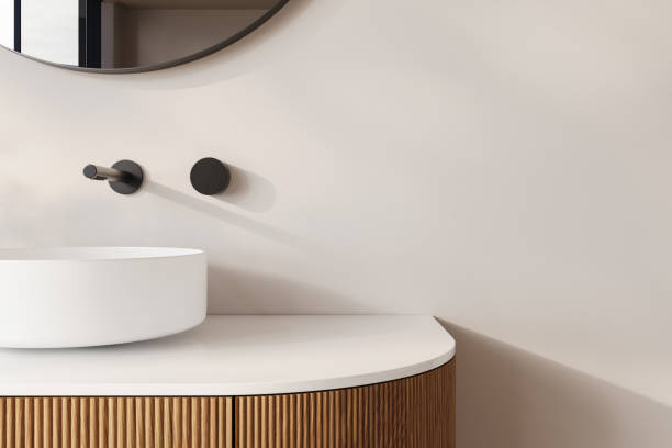 istock A rounded white basin sits atop a fluted wooden vanity, complemented by a circular mirror and minimalist decor. This bathroom design highlights a blend of modern elegance and natural textures. 2192348707