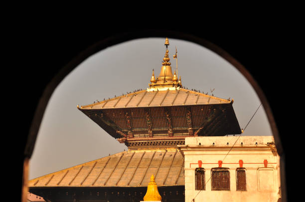 Pashupatinath's tiered golden roof and intricate details, framed by an arch.1 A glimpse of sacred architecture.