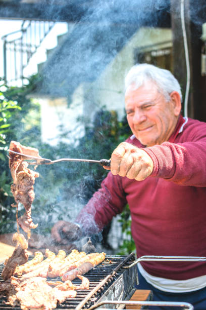 istock Grandfather cooking on barbecue outdoors in garden 2192352610