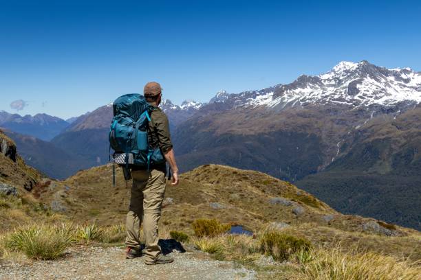 istock Hiker on Mountain Trail with Snowy Peaks 2192353898