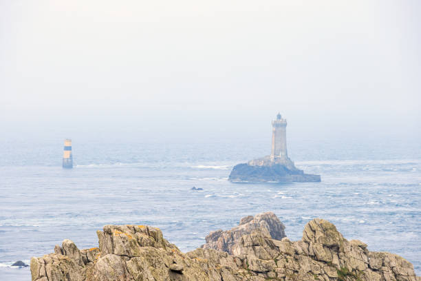 Awesome seascape view with a lighthouse on a rock and a misty sea