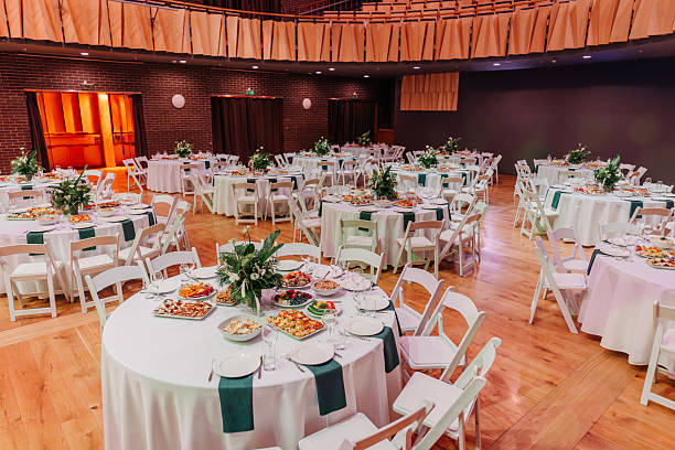 istock Elegant banquet hall with round tables set for an event, featuring white tablecloths, green napkins, and floral centerpieces. 2192354990