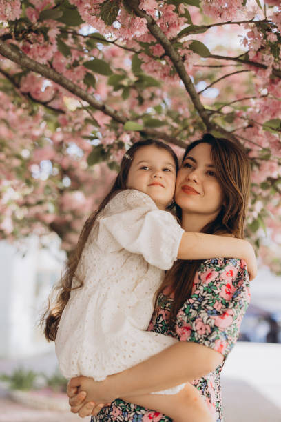 istock Mother holding her daughter under blooming sakura tree 2192363065