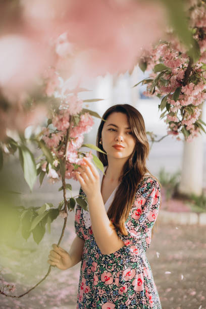 istock Young woman gently touching blooming sakura branch in spring 2192363205