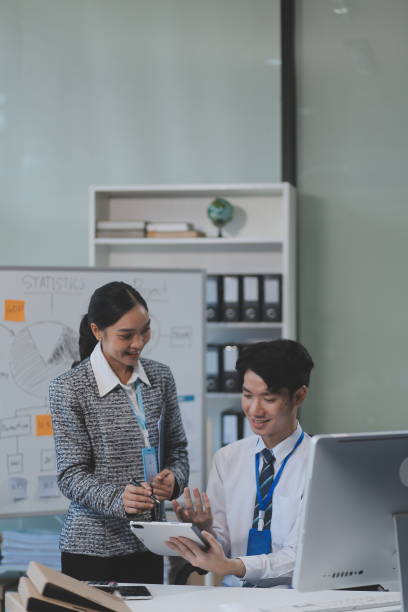 istock Cheerful businesspeople using a laptop in an office. Happy young entrepreneurs smiling while working together in a modern workspace. Two young businesspeople sitting together at a table. 2192367770